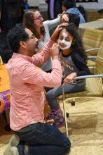 Smiling participants paint one another's faces in Day of the Dead style